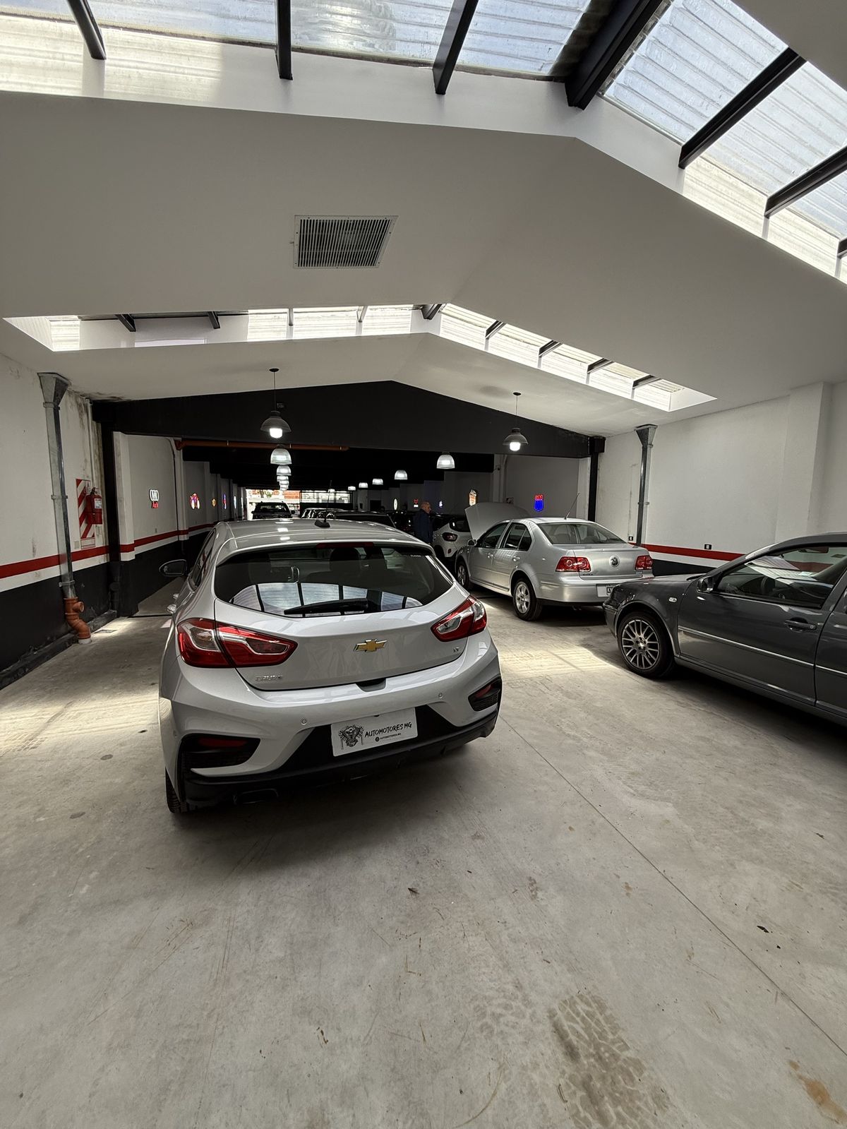 Salón de exhibición con techo vidriado y autos estacionados